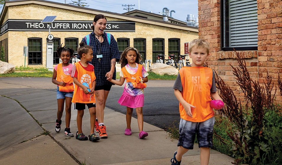 A Goodman Community Center staff member leads children on an outing away from the center.