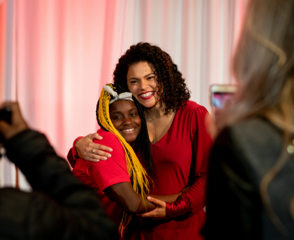 A mixed-race woman hugs a young Black girl at a gala celebrating Girls Inc. of Greater Madison.