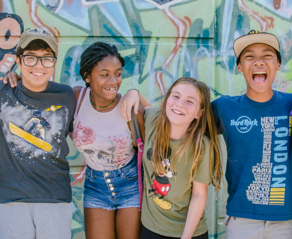 Four students smile in front of a graffiti mural in Madison, Wisconsin.