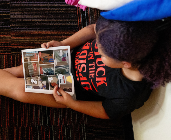 A young girl reads a graphic novel in the Goodman Community Center after-school program.
