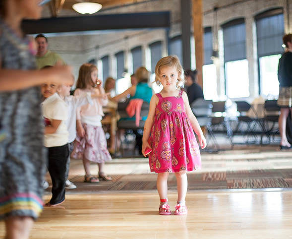A little girl in a pink dress on a dance floor at a wedding reception