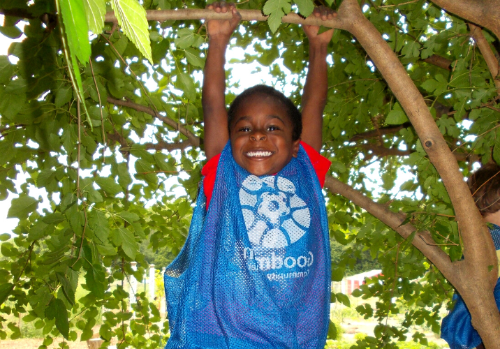 Malyki hangs from a tree wearing a Goodman shirt, age 3.