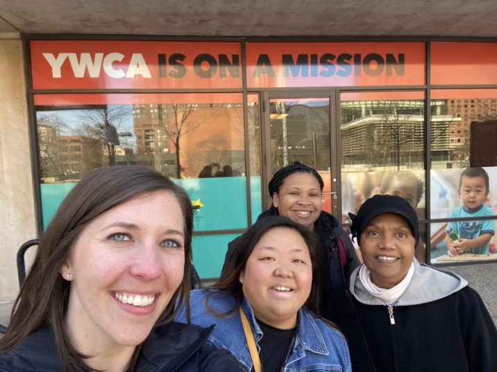 Four women stand in front of the YWCA in Minneapolis smiling for the camera.
