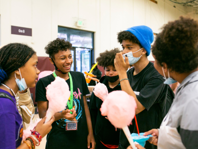 Teens talk while eating cotton candy at the Goodman family fun night.
