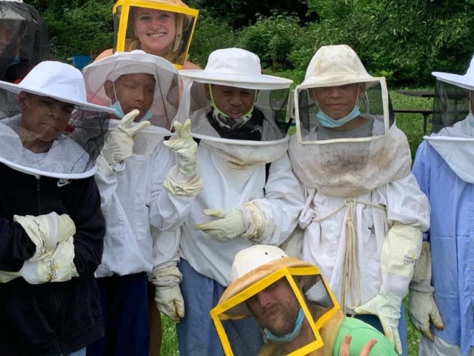 A group of teenage boys in beekeeping outfits