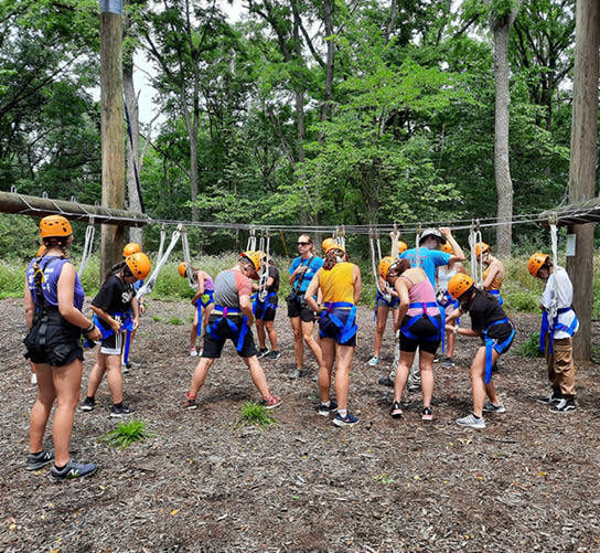 A group of girls wearing helmets doing a ropes course