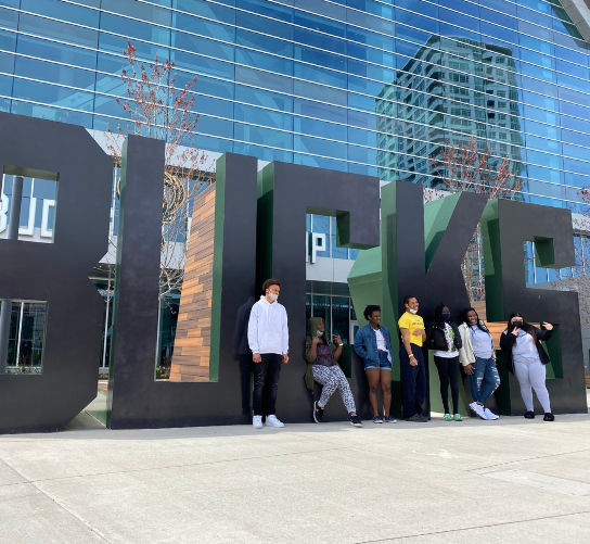 Students pose in front of oversized letters spelling out Bucks. They took a field trip to tour the Fiserv center.