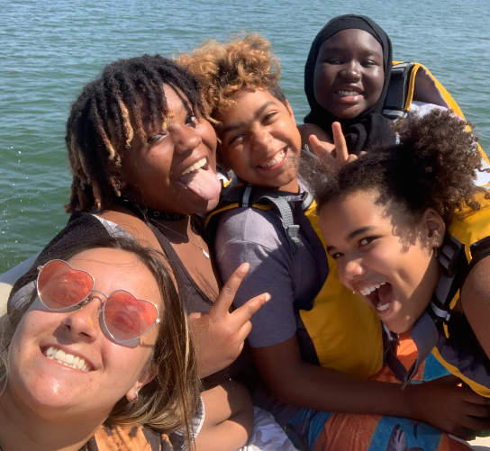 A group of middle school students and GCC staff make funny faces from a boat on Lake Monona.