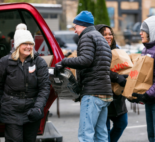 Volunteers load up a car with Thanksgiving groceries at the Goodman Center Thanksgiving Basket Drive.