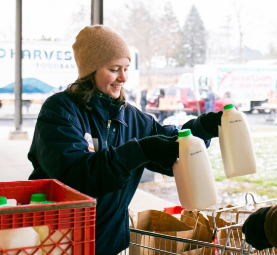 A volunteer puts milk into a cart at the Goodman Center Thanksgiving Basket Drive.