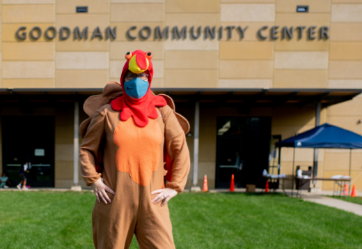 A woman in a turkey costume poses in front of the Goodman Community Center.