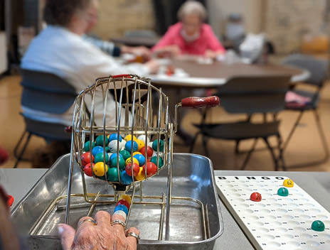 A Bingo ball spinner with women playing Bingo in the background