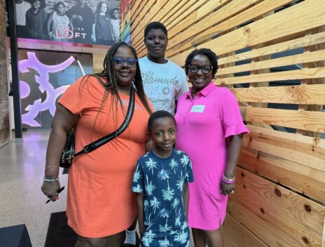 Letesha (in pink) stands with a Goodman family--mom and two boys, one teen and one elementary age--for a group photo.