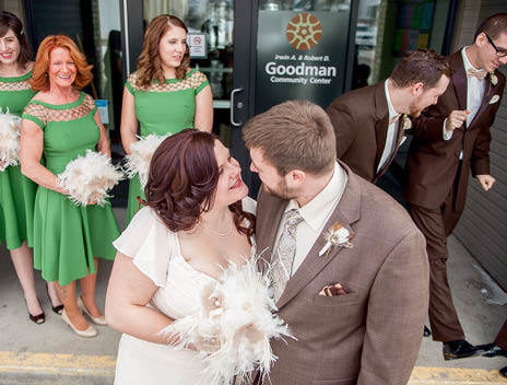 A bride and groom smiling at each other with their wedding party in the background