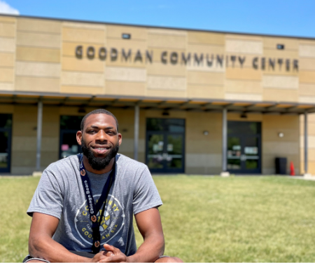 A young man sits in front of the Goodman Community Center
