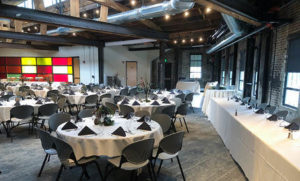 An industrial event space set up for a wedding with a colorful glass window