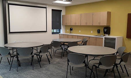 A community meeting room with a kitchenette set up with tables and chairs