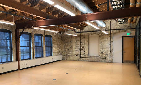 An empty industrial room with exposed ceiling beams and brick walls